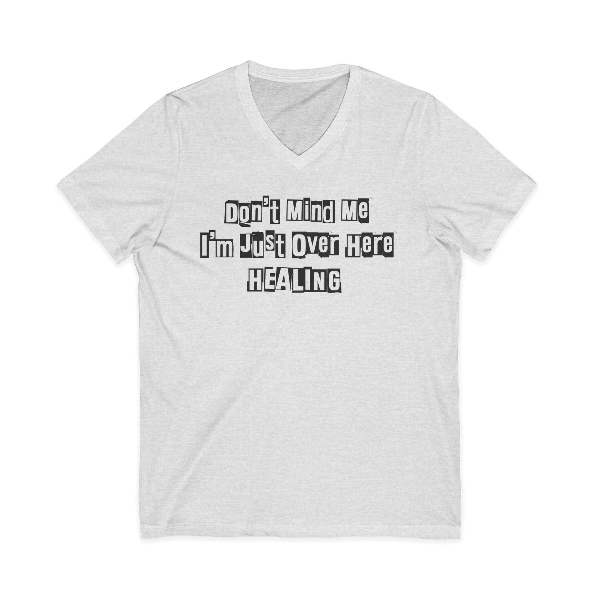 Sport grey JohnT V-neck T-shirt with the printed text “Don’t Mind Me I’m Just Over Here Healing” displayed flat on a plain background.